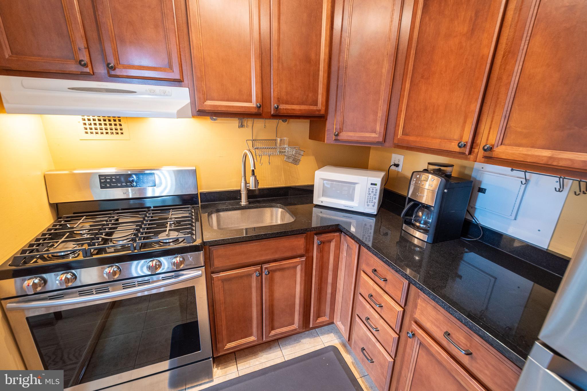 1225 Martha Custis Drive, Unit 502 Alexandria, VA 22302 - Photo 8 of 24 a kitchen with stainless steel appliances granite countertop a stove a sink and a microwave