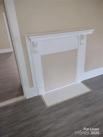 a view of an empty room with wooden floor and stairs