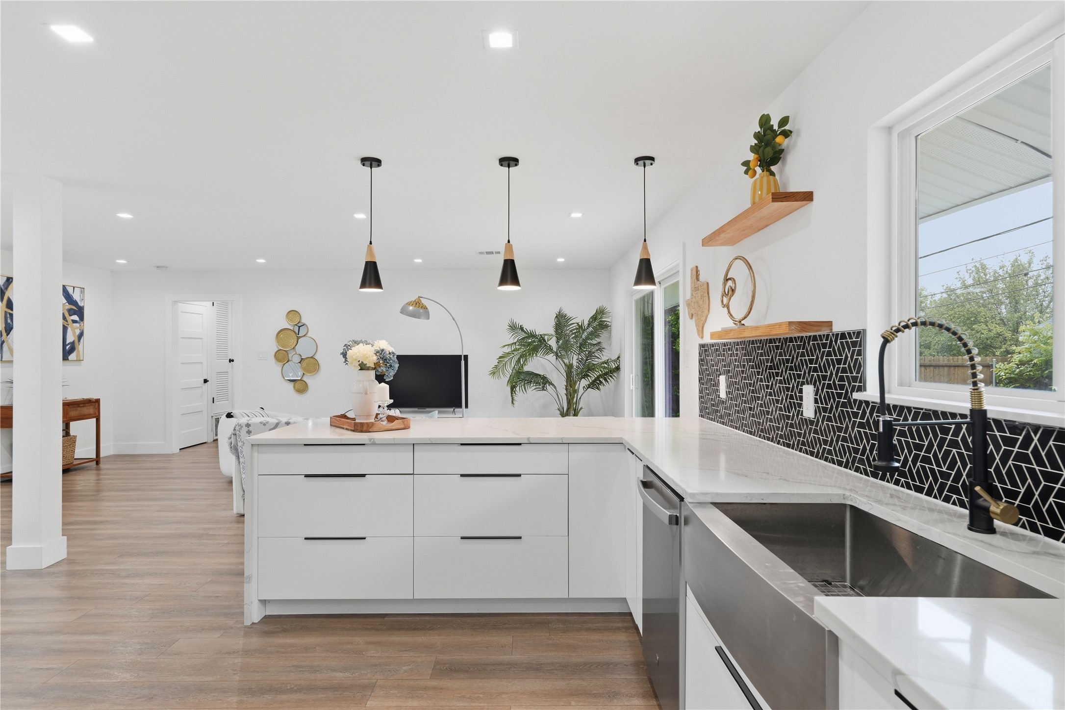5604 Coventry Lane Austin, TX 78723 - Photo 12 of 33 Kitchen featuring white cabinetry, quartz countertops, a stainless steel farmhouse sink, and a black geometric tile backsplash