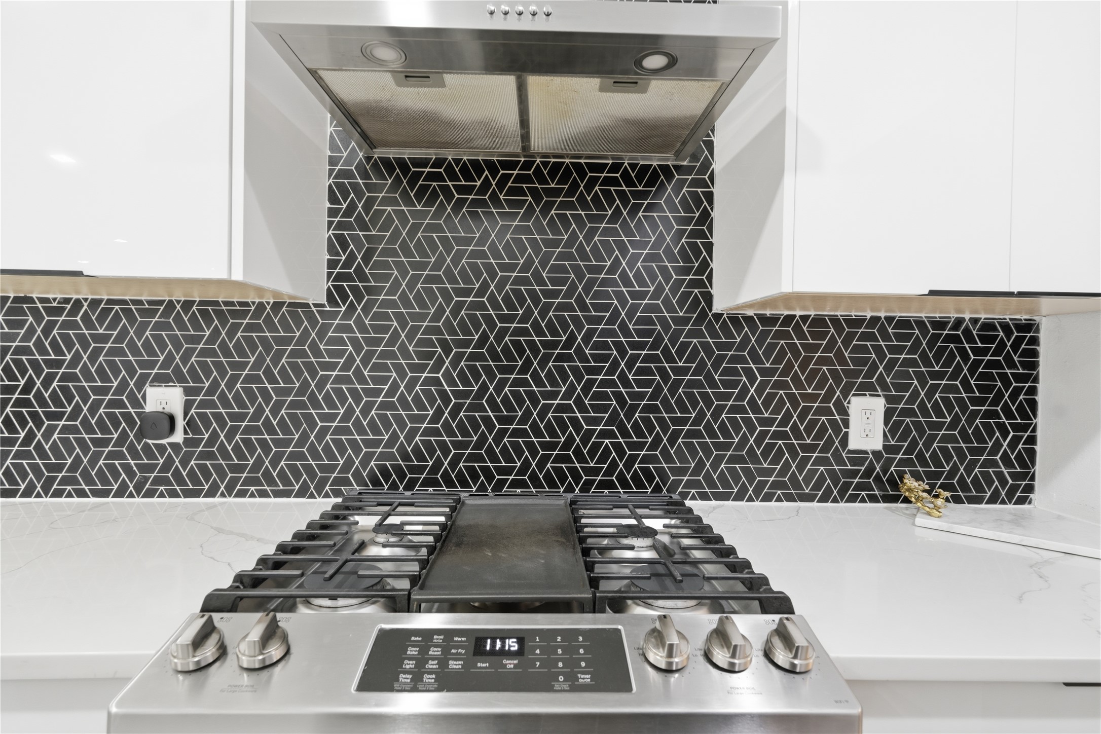 5604 Coventry Lane Austin, TX 78723 - Photo 14 of 33 Stainless steel range with an integrated griddle, a geometric pattern tile backsplash, and a stainless steel range hood