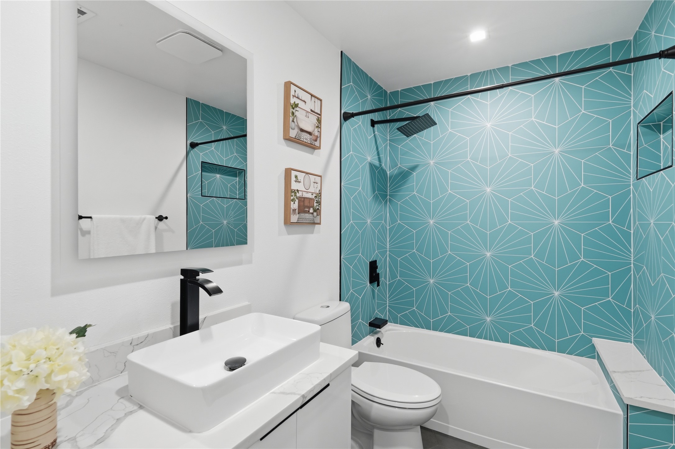 5604 Coventry Lane Austin, TX 78723 - Photo 16 of 33 Bathroom featuring a turquoise geometric tile shower surround with a built-in niche, a rainfall showerhead, and matte black fixtures