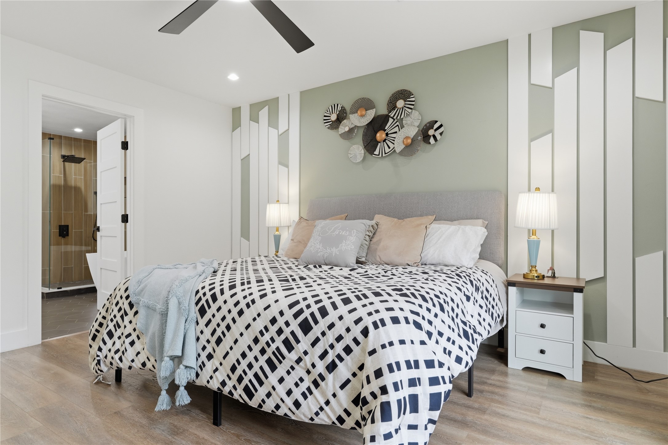 5604 Coventry Lane Austin, TX 78723 - Photo 20 of 33 Bedroom featuring an accent wall with geometric paneling, wood-finish flooring, a contemporary ceiling fan, recessed lighting, and a doorway to a bathroom with a glass-enclosed shower