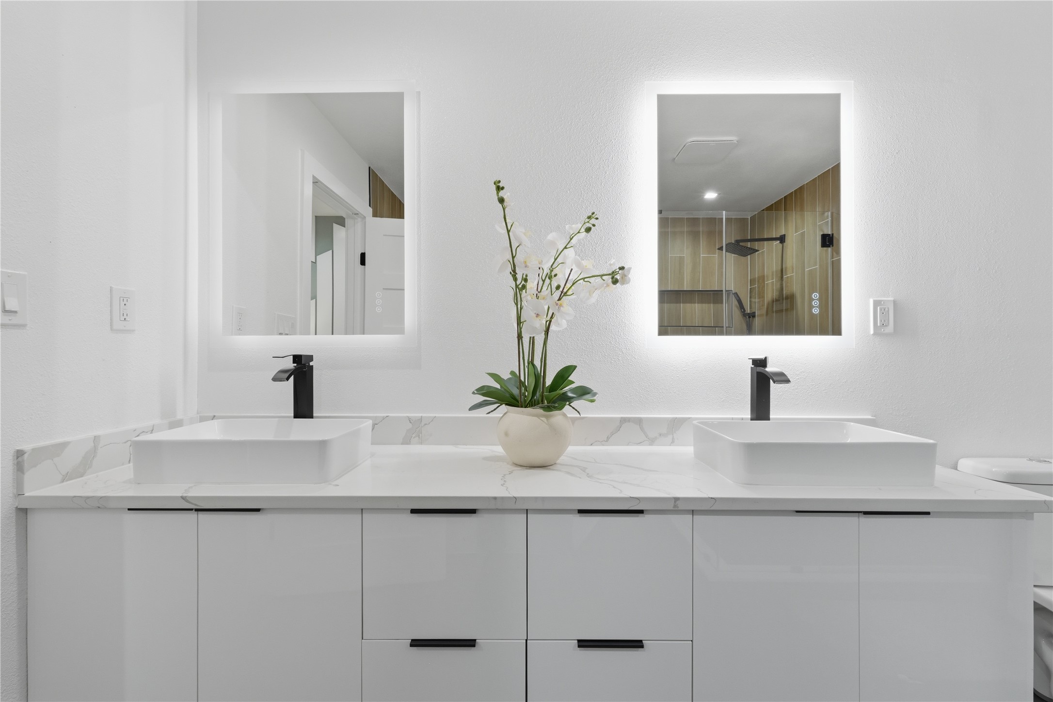 5604 Coventry Lane Austin, TX 78723 - Photo 22 of 33 Double vanity featuring an integrated countertop with two vessel sinks, matte black faucets, and back-lit mirrors