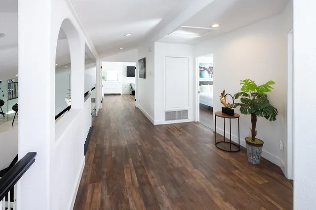 a view of a hallway with wooden floor and a potted plant
