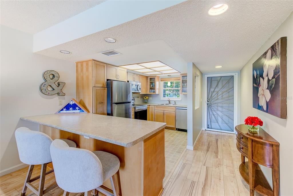 12900 Vonn Road, Unit E205 Largo, FL 33774 - Photo 2 of 35 a living room with kitchen view and wooden floor