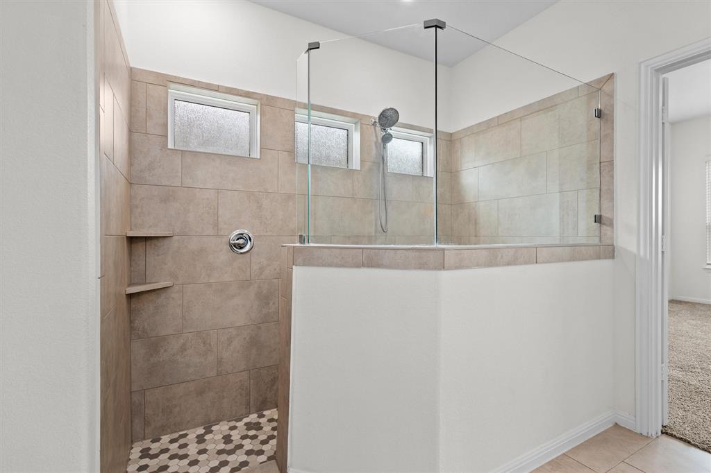 236 Prato Place Georgetown, TX 78628 - Photo 21 of 40 A spacious, glass-enclosed shower boasts tiled walls and floor, complete with built-in shelves and an adjustable shower head.