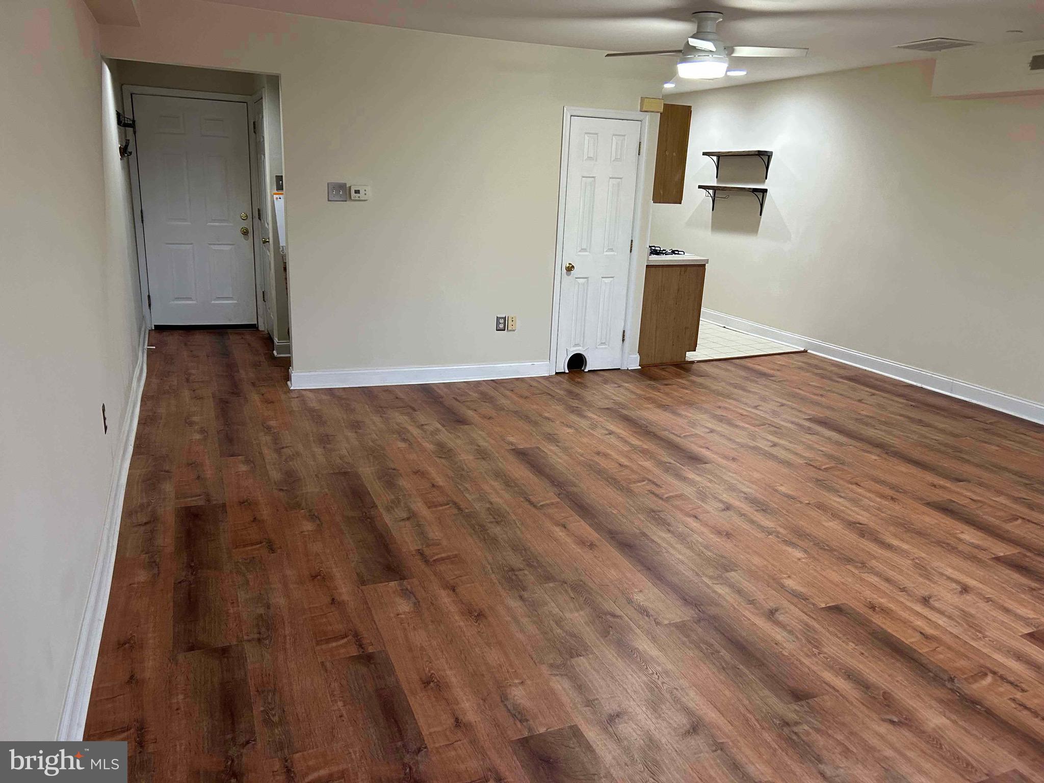 4127 Cresson Street, Unit 2F Philadelphia, PA 19127 - Photo 4 of 14 an empty room with wooden floor and kitchen view