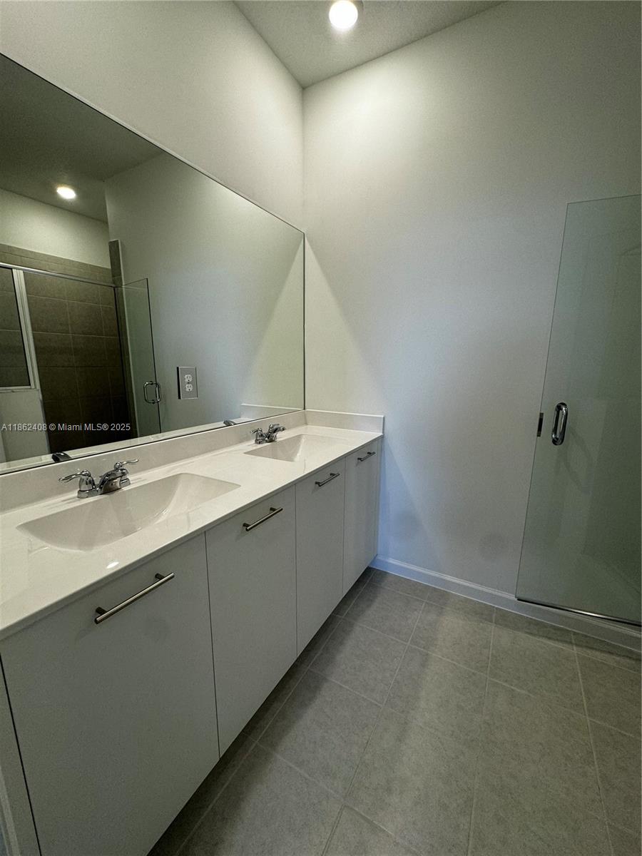 2325 Northwest 125 Street, Unit 2325 Miami, FL 33167 - Photo 14 of 18 a bathroom with a double vanity sink a large mirror and a bathtub