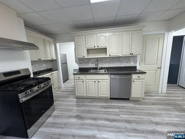 a kitchen with stainless steel appliances granite countertop a stove a sink and a refrigerator