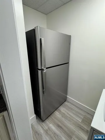 a view of a refrigerator in kitchen and an empty room