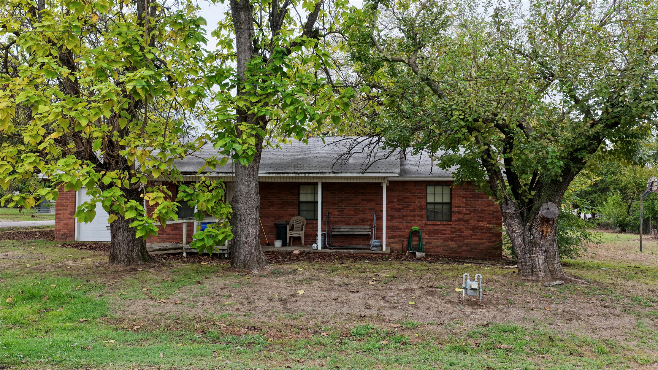 602 Northwest 4th Street Checotah, OK 74426 - Photo 1 of 28 Brick exterior with a covered porch, white columns, and mature trees
