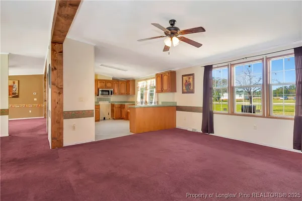 a view of an empty room with a window and kitchen view