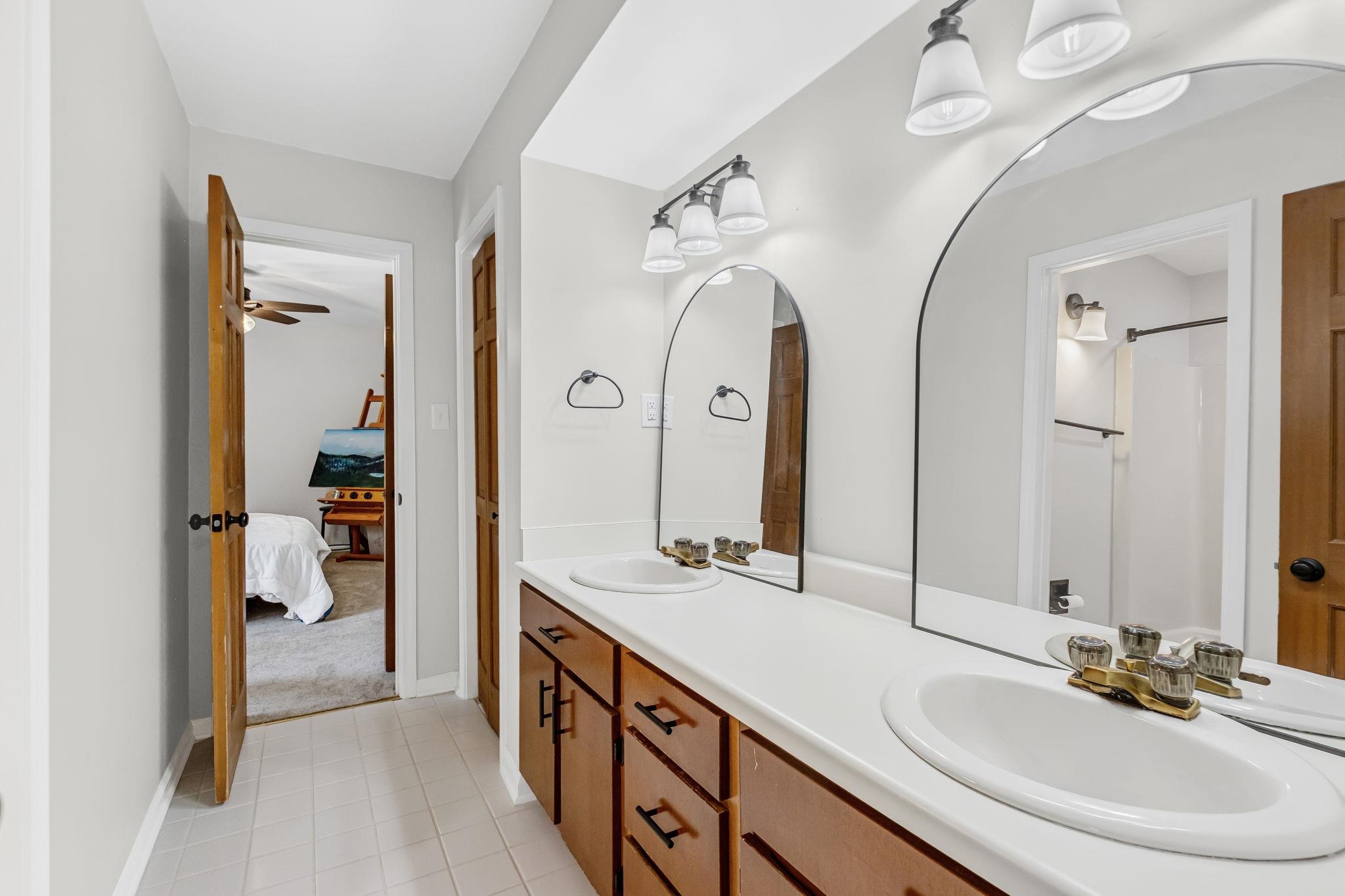 4729 Cedar Ridge Drive Millington, TN 38053 - Photo 28 of 40 Bathroom featuring a double vanity with an integrated white countertop, dual undermount sinks, and two arched mirrors