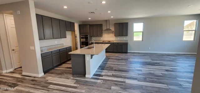 a kitchen with kitchen island granite countertop wooden floors and wide window