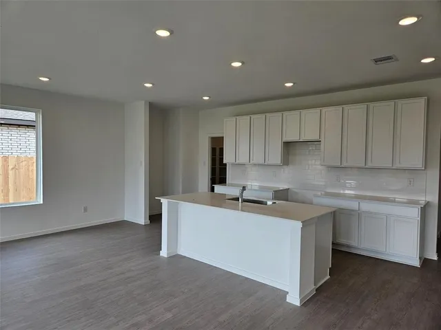 a kitchen with stainless steel appliances kitchen island granite countertop a table chairs in it and white cabinets