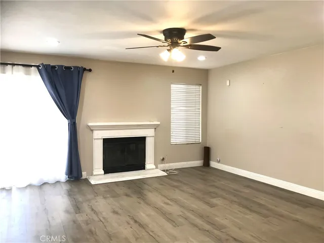 an empty room with wooden floor fireplace and windows