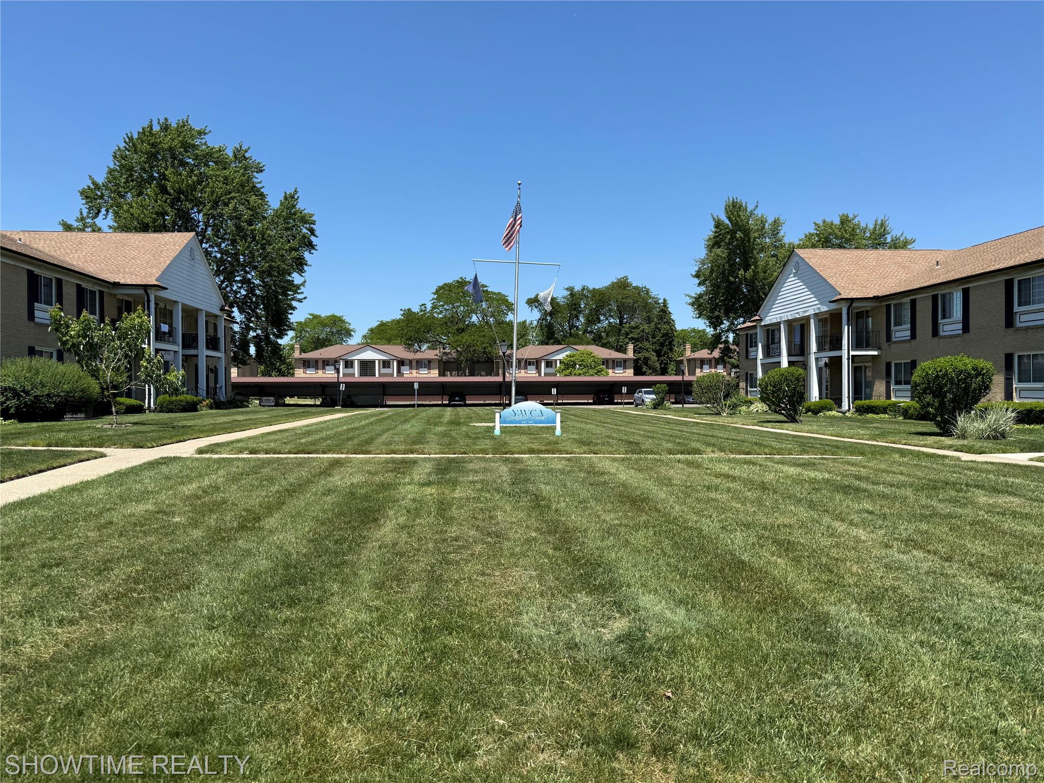 29141 Hayes Road Warren, MI 48088 - Photo 18 of 18 Expansive lawn with mature trees, paved walkways, and multi-story buildings featuring balconies