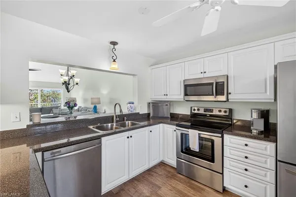 a kitchen with stainless steel appliances granite countertop white cabinets a sink a stove and a microwave