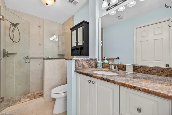 a bathroom with a granite countertop sink toilet and shower