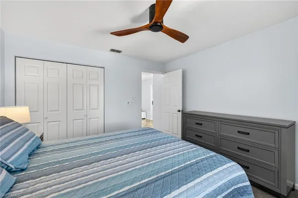 a bedroom with a bed and a lamp on a dresser
