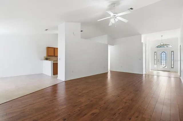 a view of a livingroom with wooden floor a ceiling fan and windows