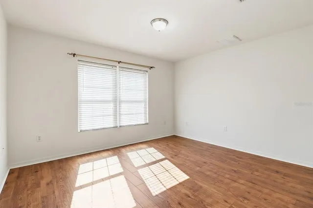 an empty room with wooden floor and windows