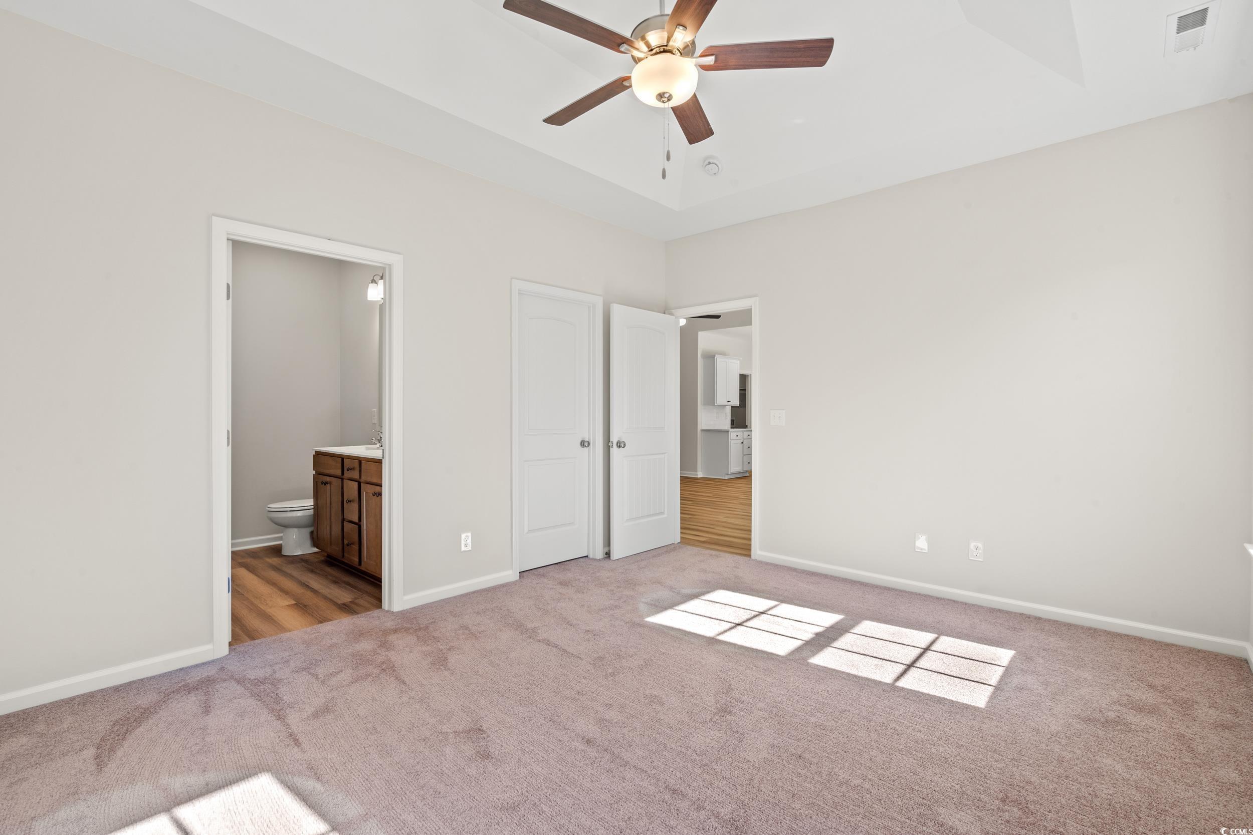 247 Stillbrook Drive Longs, SC 29568 - Photo 13 of 36 Unfurnished bedroom featuring carpet flooring, a ceiling fan, ensuite bathroom, and a tray ceiling