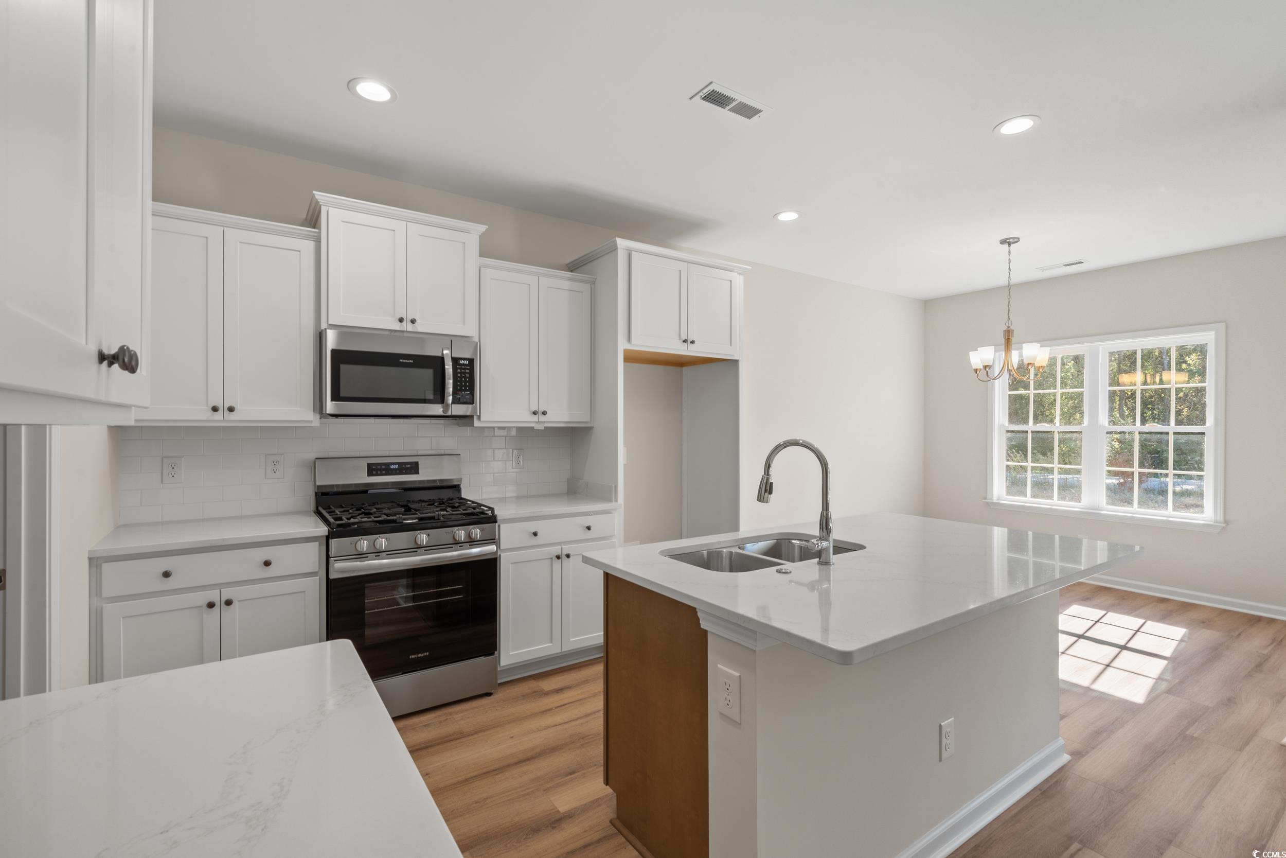 247 Stillbrook Drive Longs, SC 29568 - Photo 14 of 36 Kitchen with appliances with stainless steel finishes, white cabinets, decorative backsplash, a kitchen island with sink, and recessed lighting