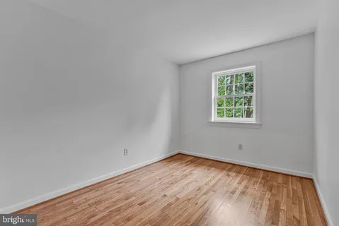 a view of a hallway with wooden floor and a bathroom