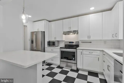 a kitchen with a sink a refrigerator and white cabinets