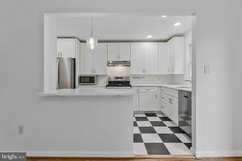 a kitchen with a sink a white cabinets and black appliances