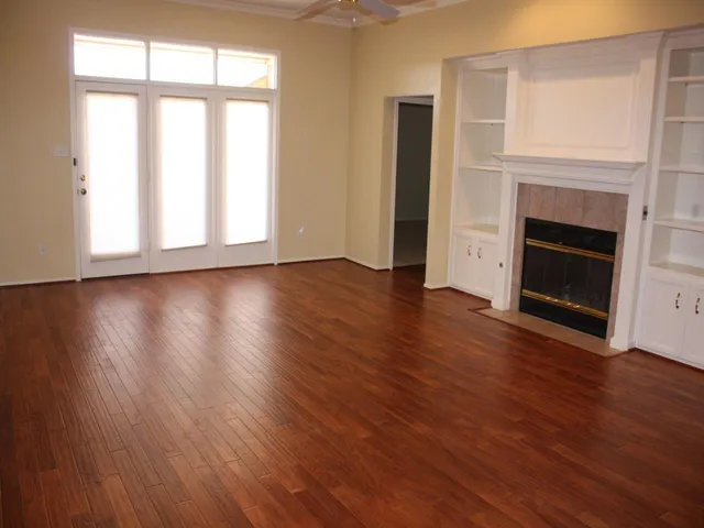 a view of an empty room with wooden floor and a window