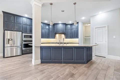 a kitchen with kitchen island granite countertop wooden cabinets and refrigerator