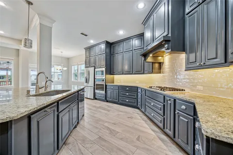 a kitchen with stainless steel appliances granite countertop a sink a stove and a wooden cabinets