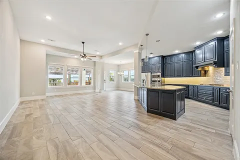 a large kitchen with stainless steel appliances kitchen island granite countertop a large counter top and wooden floors