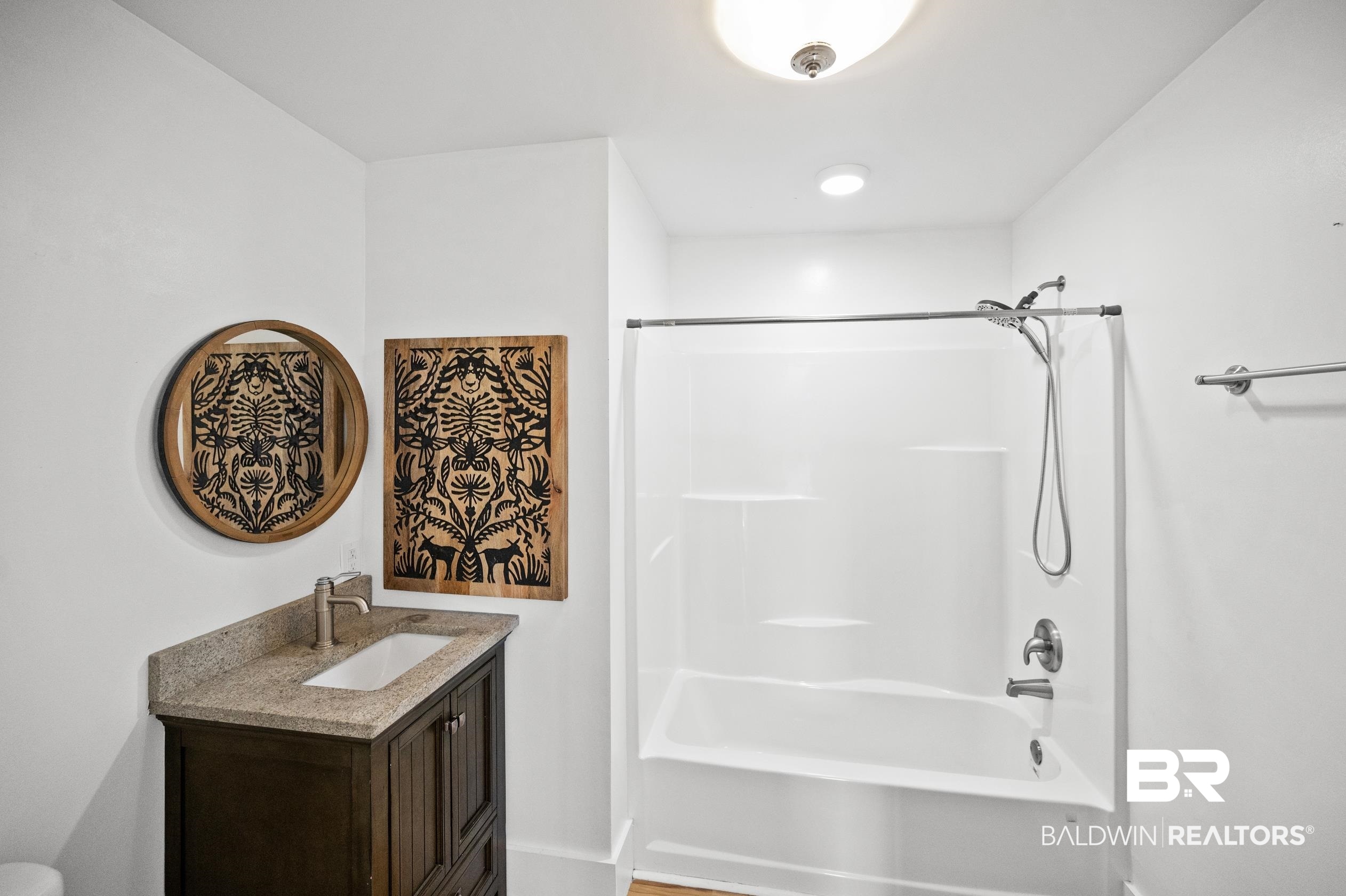 24663 Chestnut Street Elberta, AL 36530 - Photo 18 of 22 Bathroom featuring a dark wood vanity with a stone countertop, an undermount sink, and a single-handle faucet