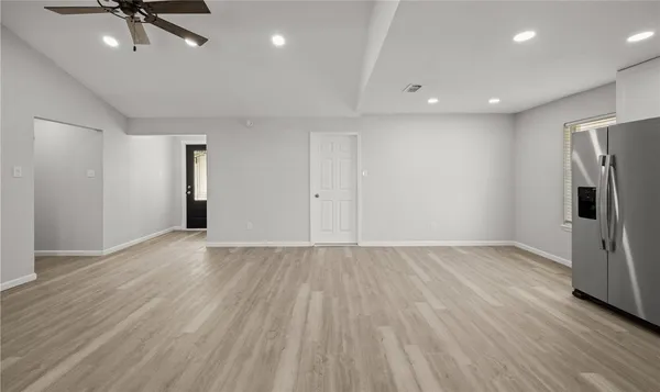 an empty room with wooden floor and a ceiling fan