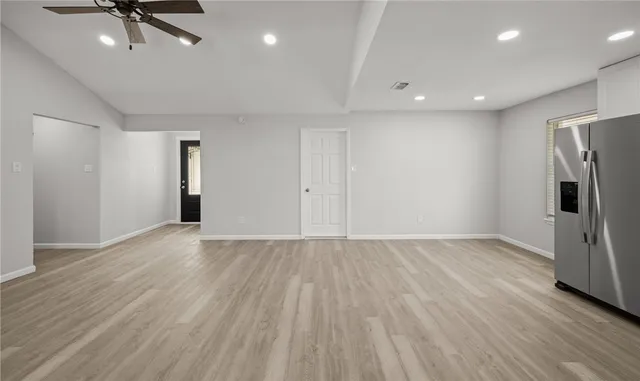 an empty room with wooden floor and a ceiling fan