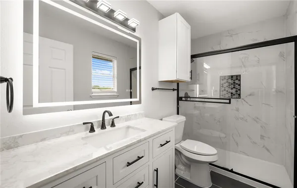 a bathroom with a granite countertop sink a toilet and a mirror