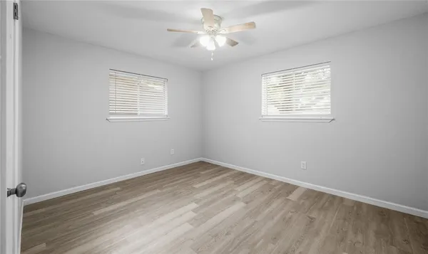 an empty room with a window and a ceiling fan