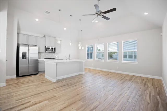 a view of an empty room with a window and wooden floor