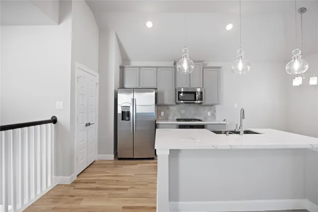 a kitchen with stainless steel appliances granite countertop a sink and wooden floor