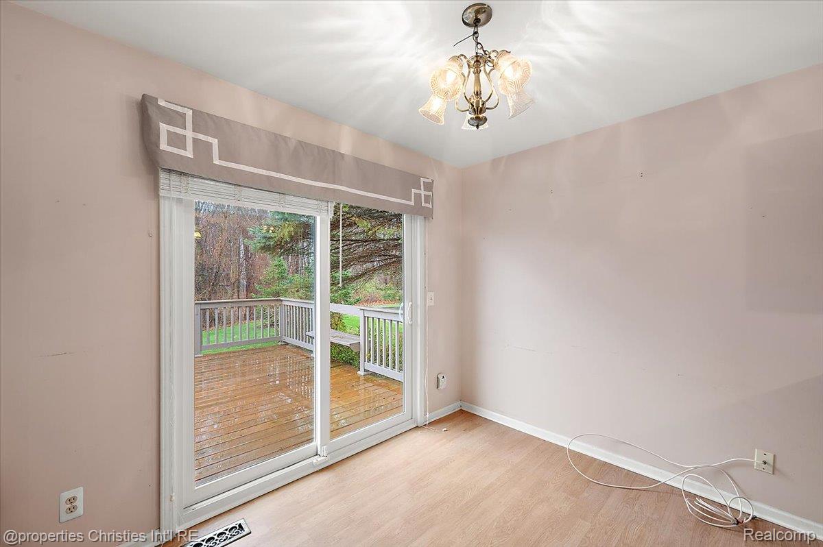 955 Rikki Ann Court Wixom, MI 48393 - Photo 27 of 54 Empty room with hanging lights and light wood finished floors