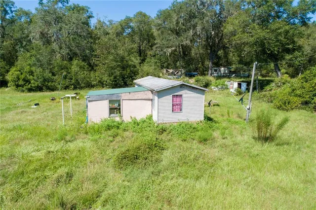 a big white house with a big yard and large trees with wooden fence