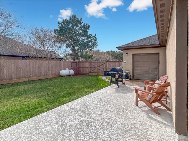 a view of a backyard with table and chairs potted plants and a large tree