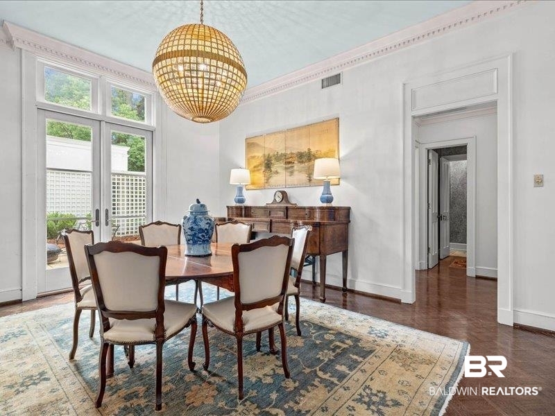 109 Eaton Square Mobile, AL 36608 - Photo 7 of 26 Formal dining space featuring French doors, a coffered ceiling with a central chandelier, wood-finish flooring, and detailed crown molding