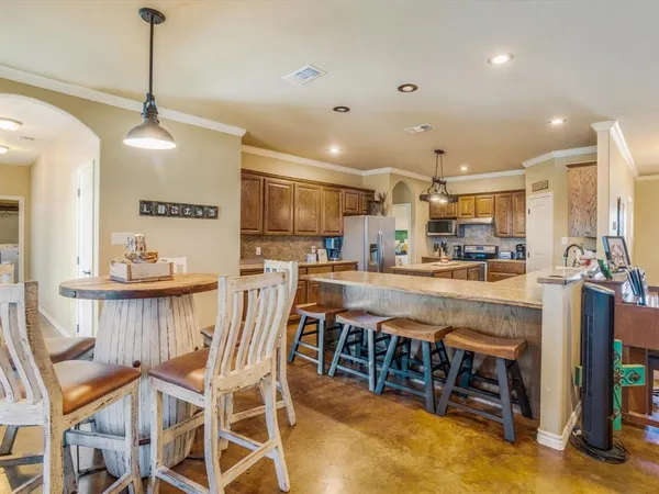 a kitchen with stainless steel appliances kitchen island granite countertop a table chairs and white cabinets