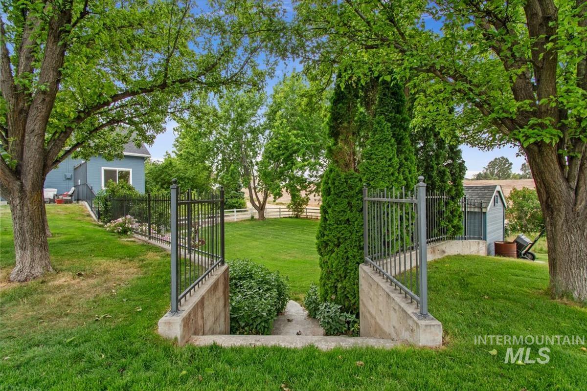 10462 West Lanktree Gulch Road Star, ID 83669 - Photo 44 of 48 Expansive backyard featuring mature trees, lush green lawn, and a black wrought iron fence