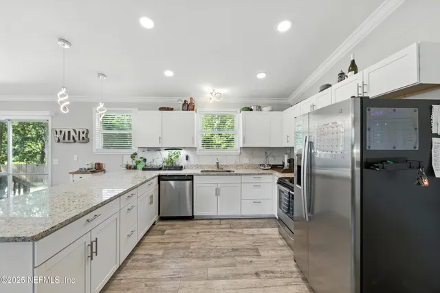 a large kitchen with stainless steel appliances granite countertop a sink stove refrigerator and cabinets