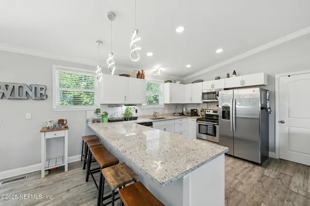 a kitchen with granite countertop a table chairs stainless steel appliances and cabinets